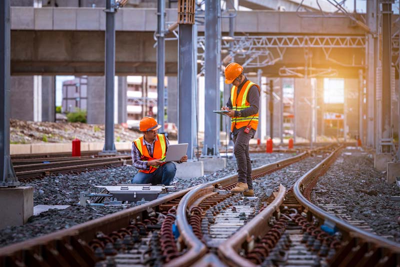 Two rail workers who have passed a Cat 3 track safety medical are on a railway line assessing the condition of the train track.